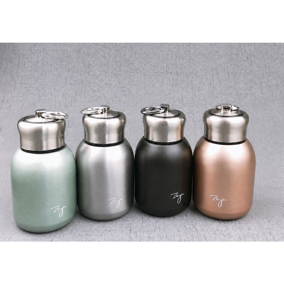 Four insulated stainless steel water bottles with screw-top lids and carrying loops, shown in mint green, silver, matte black, and rose gold on a gray textured background.