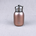 Compact insulated bottle in rose gold, with stainless-steel lid and metal carrying loop.