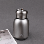 Compact insulated bottle in silver, with stainless-steel lid and metal carrying loop.
