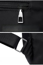 Close-up of a black sling bag showing a silver metal zipper pull and a black adjustable strap with a silver metal buckle, on a white background.